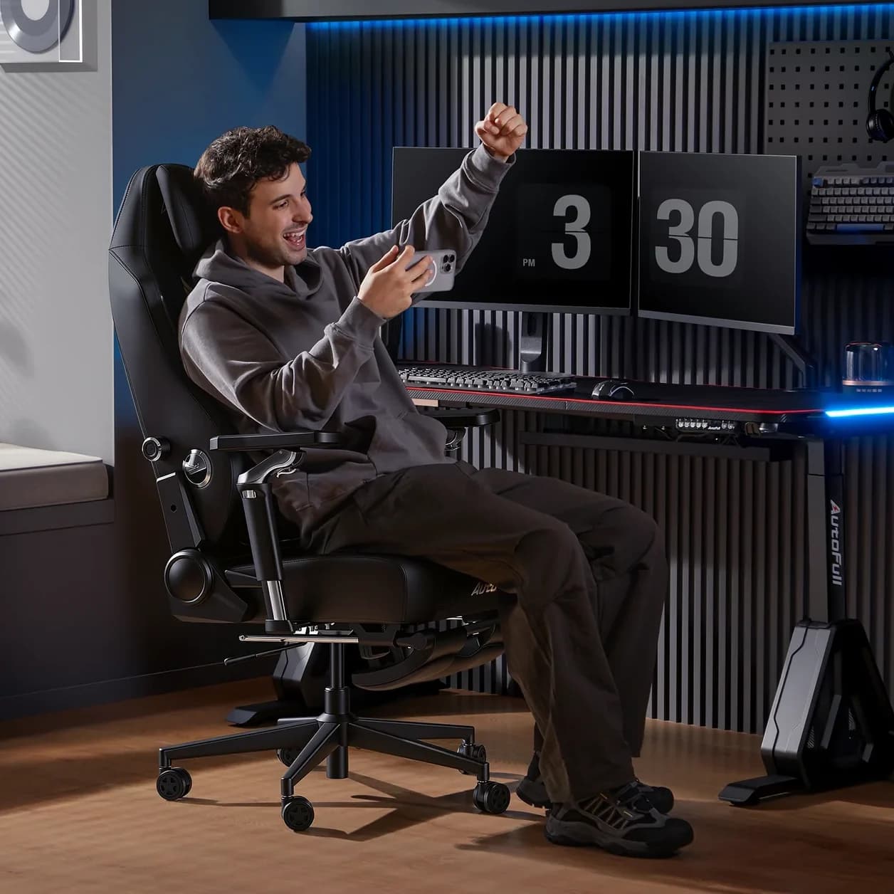 Man in a gray hoodie sitting in a black ergonomic gaming chair.